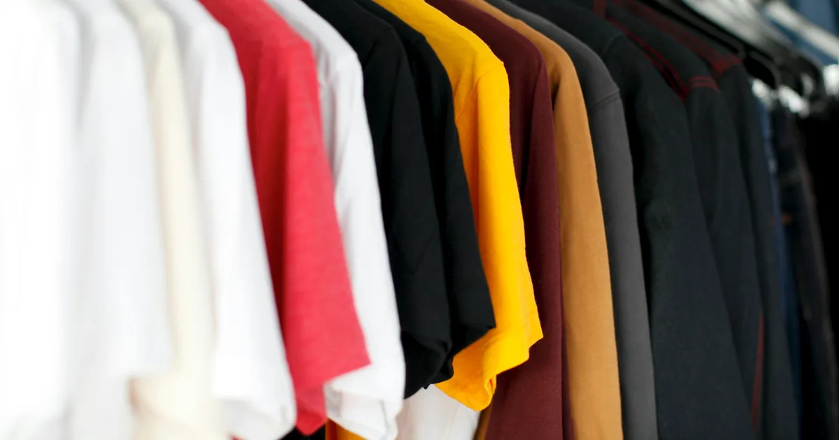 Rows of colorful printed t-shirts hanging on a retail rack ready for shipping