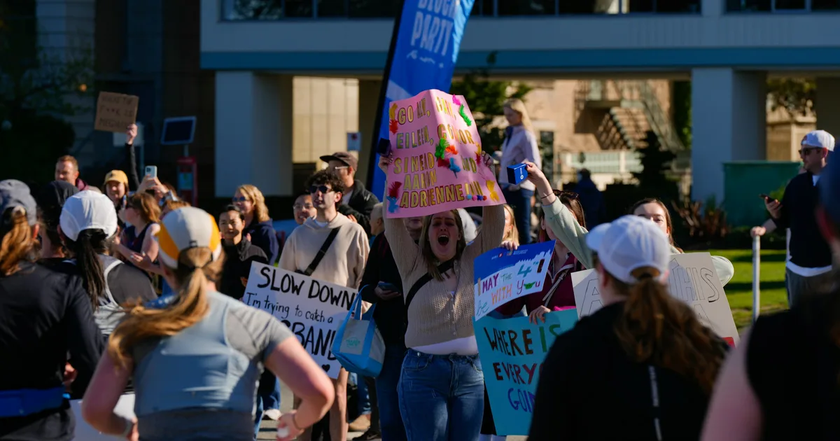 Marathon spectators along the course holding handmade cheer signs as runners pass