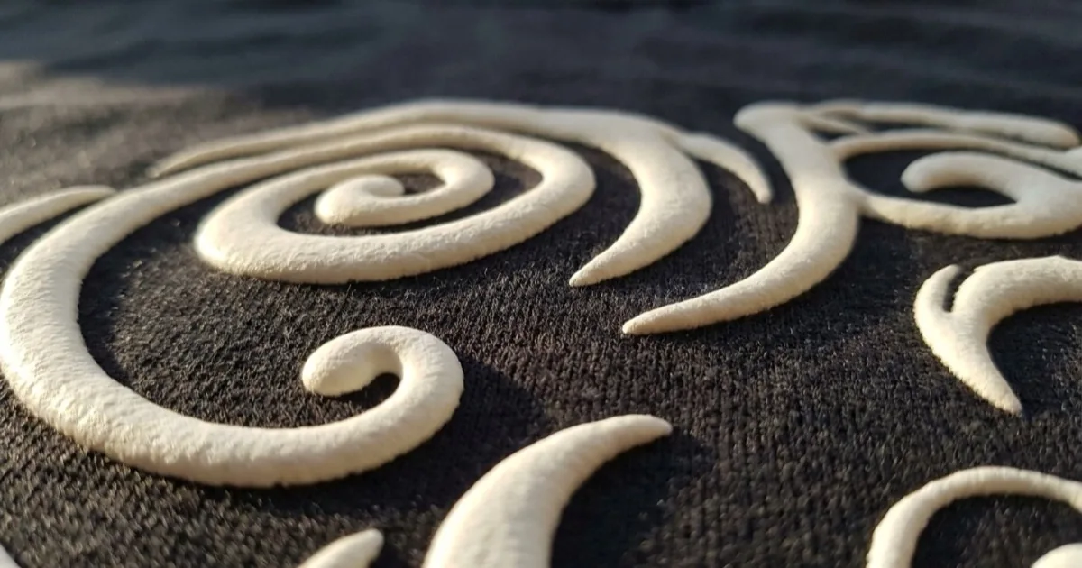 Close-up of raised puff ink standing proud of the knit fabric surface on a dark t-shirt