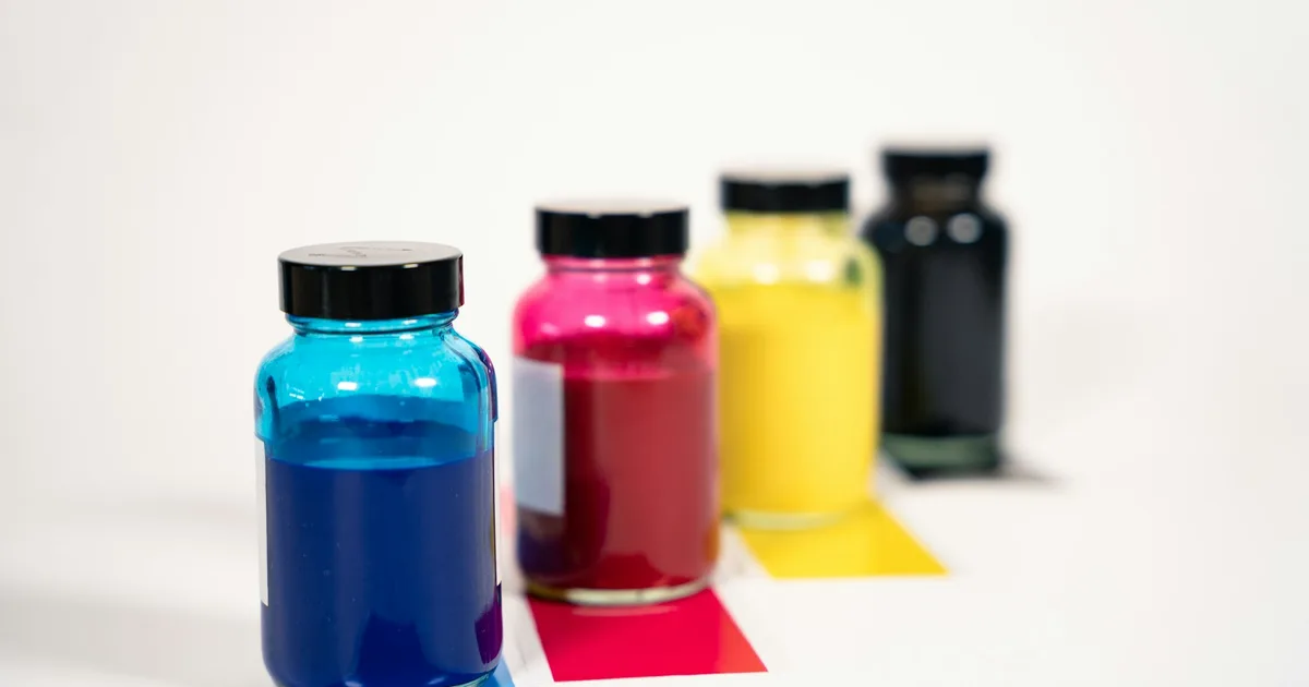 Row of bulk printer ink bottles in multiple colors used for refilling DTF printer ink tanks
