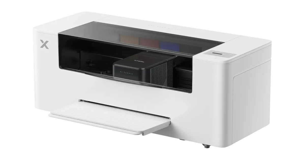 xTool Apparel Printer Plus, a white desktop DTF printer with a tinted top window, an AI camera carriage, and a front film tray